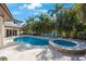 Backyard pool and hot tub surrounded by lush tropical landscaping and travertine patio at 597 Bay St, Palm Harbor, FL 34683
