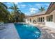 Beautiful backyard pool with travertine patio, outdoor seating area, and lush tropical landscaping at 597 Bay St, Palm Harbor, FL 34683