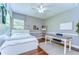 Cozy bedroom with a white bed, desk, ceiling fan, hardwood floors, and natural light at 6112 Ibispark Dr, Lithia, FL 33547