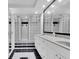 Modern bathroom featuring double sinks, glass block window and shower, and striking black and white flooring at 630 48Th N Ave, St Petersburg, FL 33703