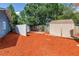 Large backyard with two sheds, offering ample storage space on red mulch and under mature trees at 6515 Dimarco Rd, Tampa, FL 33634