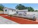 Back of house with a wooden deck and picnic tables surrounded by red mulch landscaping at 6515 Dimarco Rd, Tampa, FL 33634