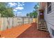 Fenced yard with red mulch ground cover, leading to stairs and a doorway at 6515 Dimarco Rd, Tampa, FL 33634