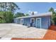 Blue exterior home with a concrete driveway, complemented by red mulch landscaping at 6515 Dimarco Rd, Tampa, FL 33634