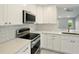 This is a kitchen with stainless steel appliances, white cabinets and counter tops, and a tile backsplash at 6994 Country Lakes Cir, Sarasota, FL 34243