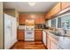 Well-lit kitchen featuring wood cabinets, white appliances, and an open counter to the living area at 7508 S Mascotte St, Tampa, FL 33616
