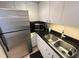 A well-lit corner of the kitchen, featuring a stainless steel refrigerator, a sink and cabinets at 880 Mandalay Ave # S511, Clearwater Beach, FL 33767