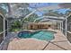 Aerial view of fenced in backyard pool area with covered patio and pool at 940 Woodland Dr, Palm Harbor, FL 34683