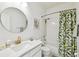 Bright bathroom with a modern vanity, circular mirror, and a shower-tub combination with a decorative curtain at 10011 Parley Dr, Tampa, FL 33626