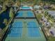 Aerial view of well-maintained community tennis courts with vibrant blue courts, next to pool and pond at 10011 Parley Dr, Tampa, FL 33626