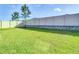 Expansive backyard featuring a well-kept lawn, a white fence, and scattered trees under a clear blue sky at 10978 Laxer Cay Loop, San Antonio, FL 33576