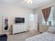 This bedroom features a TV, cabinet with drawers, carpeted floors, and natural light coming through the windows at 10978 Laxer Cay Loop, San Antonio, FL 33576