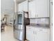 Modern kitchen with stainless steel appliances, granite countertops, and sleek white cabinetry, offering ample storage at 10978 Laxer Cay Loop, San Antonio, FL 33576