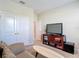 Living room featuring a cozy sofa, TV, storage shelves, and plenty of natural light from the window at 10978 Laxer Cay Loop, San Antonio, FL 33576