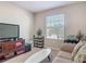 This living room has a comfortable sofa, TV, storage shelves, and plenty of natural light from the window at 10978 Laxer Cay Loop, San Antonio, FL 33576
