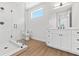 Modern bathroom with glass-enclosed shower, white cabinets, and wood-look flooring at 11 29Th N St, St Petersburg, FL 33713