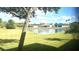 Scenic backyard with a serene pond view, lush green grass, and neighborhood homes in the distance under a blue sky at 11468 Captiva Kay Dr, Riverview, FL 33569