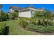 Beautifully landscaped front yard with lush greenery, mature palms, and a light green exterior at 13539 Circa Crossing Dr, Lithia, FL 33547