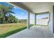 View from the covered patio overlooking a large yard with a fence and a lake in the distance at 13757 Wineberry Dr, Dade City, FL 33525