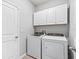 Laundry room with white cabinets above modern washer and dryer units at 13757 Wineberry Dr, Dade City, FL 33525