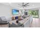 Bright, open living room with a large sectional sofa, tile flooring, and sliding glass doors to the backyard at 13757 Wineberry Dr, Dade City, FL 33525