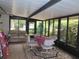 Enclosed sunroom with a dining table, chairs, and views of the surrounding greenery at 1395 Heather Ridge Blvd, Dunedin, FL 34698