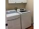 Bright laundry room featuring a full-sized white washer and dryer set and above storage cabinets at 1415 Saddle Gold Ct, Brandon, FL 33511