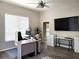 A well-lit office space featuring a ceiling fan, a television and grey wood-look floors at 16106 Bridgedale Dr, Lithia, FL 33547