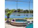 Screened-in patio with in-ground spa, lake view, and palm tree in a pot at 16106 Bridgedale Dr, Lithia, FL 33547