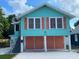 Charming raised cottage home with turquoise siding, coral shutters, and a two-car garage at 1626 27Th N Ave, St Petersburg, FL 33713