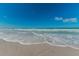 White sand beach with clear blue water and gentle waves at 1700 Pass A Grille Way # 9, St Pete Beach, FL 33706
