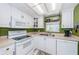 Well-lit kitchen with white appliances, cabinets, and green accent wall, with a window view at 1700 Pass A Grille Way # 9, St Pete Beach, FL 33706