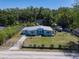 An elevated view showcasing a quaint blue home with a fenced yard, nestled among lush greenery at 17111 Mockingbird Ln, Lutz, FL 33548