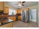 Well-lit kitchen with stainless steel refrigerator and wood cabinets, next to bathroom at 17111 Mockingbird Ln, Lutz, FL 33548