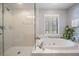 Bright bathroom showcasing a walk-in shower and soaking tub with tile surround and a window with shutters at 17537 Fairmeadow Dr, Tampa, FL 33647