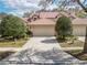 Exterior view of home with a spacious two-car garage, tile roof, and beautiful landscaping at 17537 Fairmeadow Dr, Tampa, FL 33647
