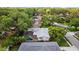Aerial view showcases a home's screened-in pool and lush backyard within a tree-filled neighborhood at 1905 Oro Ct, Clearwater, FL 33764