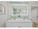Bright bathroom with a double sink vanity, decorative mirror, and blue accent wall at 1905 Oro Ct, Clearwater, FL 33764