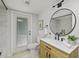 Well-lit bathroom with a modern vanity, round mirror, and walk-in shower with marble-look tile at 1905 Oro Ct, Clearwater, FL 33764