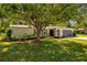 Charming home exterior with lush greenery, a well-maintained lawn, and a stylish, arched garage entrance at 1905 Oro Ct, Clearwater, FL 33764
