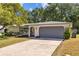 A charming single-story home featuring a gray garage door and well-manicured landscaping with mature trees at 1905 Oro Ct, Clearwater, FL 33764