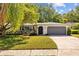 Charming single-story home with a well-manicured lawn, gray garage door, and an arched entryway at 1905 Oro Ct, Clearwater, FL 33764