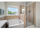 Bathroom showcasing a garden tub and glass enclosed shower with tiled surround and bright natural light at 19278 Roseate Dr, Lutz, FL 33558