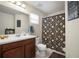 A well-lit bathroom featuring a single sink vanity, toilet, and a shower-tub combination with patterned curtain at 19278 Roseate Dr, Lutz, FL 33558