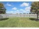Picturesque backyard with a well-maintained lawn, white picket fence, and serene lake view providing a peaceful oasis at 19796 Long Lake Ranch Blvd, Lutz, FL 33558