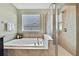 Inviting bathroom showcasing soaking tub, walk-in shower, and travertine tiled walls at 19796 Long Lake Ranch Blvd, Lutz, FL 33558