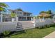 Expansive backyard with multiple outdoor seating areas, lush landscaping, and steps leading down to the lawn at 213 Harrison Ave, Belleair Beach, FL 33786
