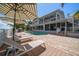 Backyard view of a waterfront home, highlighting a spacious patio, outdoor seating, pool, and lush landscaping at 213 Harrison Ave, Belleair Beach, FL 33786