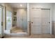 Bright bathroom featuring beige tiles, glass enclosed shower with bench, and white doors at 213 Harrison Ave, Belleair Beach, FL 33786