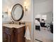 Bathroom with dark wood vanity, decorative mirror, sconces, and view of the Primary bedroom at 213 Harrison Ave, Belleair Beach, FL 33786